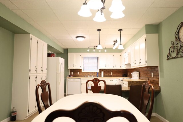 dining space featuring a paneled ceiling, a chandelier, and sink