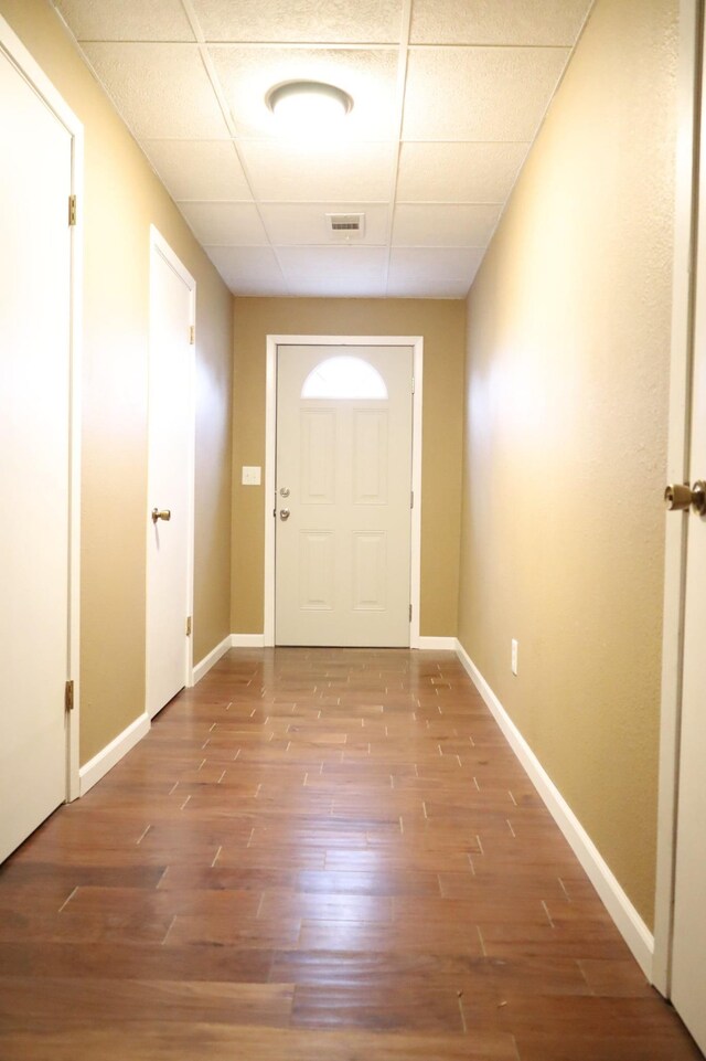 doorway with hardwood / wood-style flooring and a drop ceiling