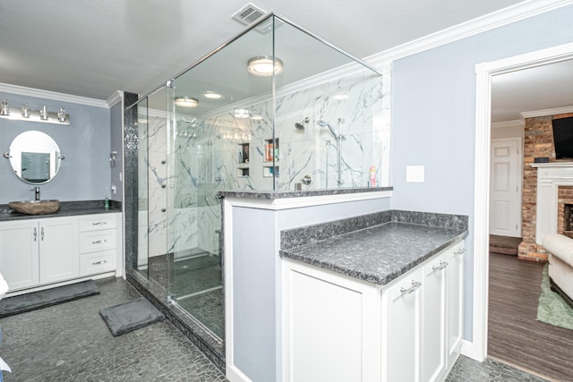 bathroom featuring crown molding, vanity, a shower with shower door, and a brick fireplace