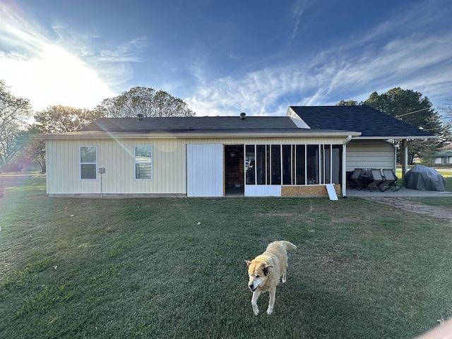 back of house featuring a sunroom and a lawn