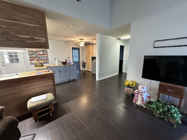 interior space featuring dark wood-type flooring, a barn door, and ceiling fan