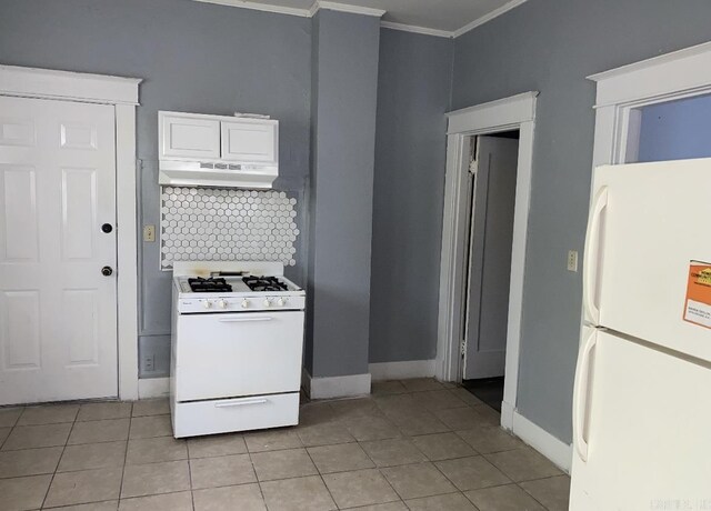 kitchen with light tile patterned floors, crown molding, white appliances, range hood, and white cabinets