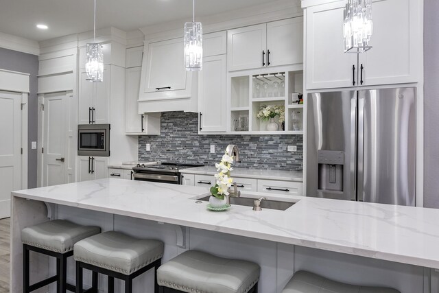 kitchen featuring stainless steel appliances, light stone countertops, hanging light fixtures, and white cabinets