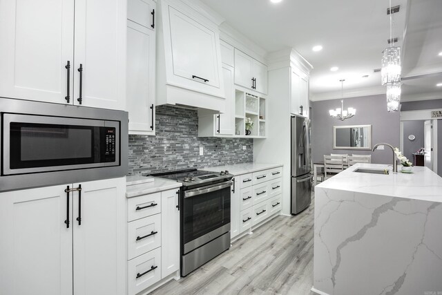 kitchen featuring white cabinetry, stainless steel appliances, decorative light fixtures, and sink