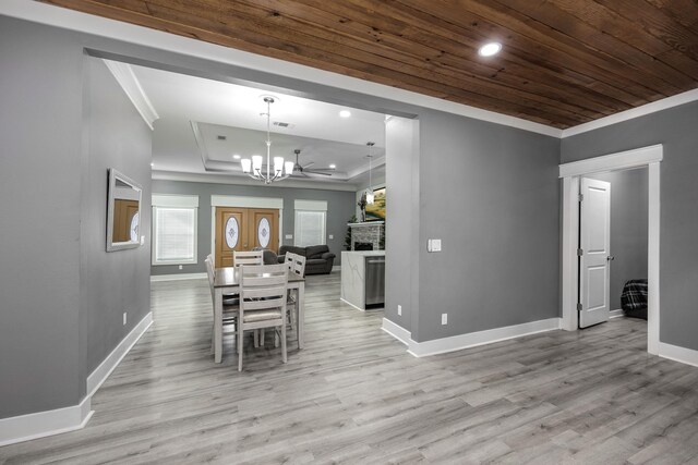 dining space featuring wood ceiling, an inviting chandelier, a tray ceiling, ornamental molding, and light hardwood / wood-style floors