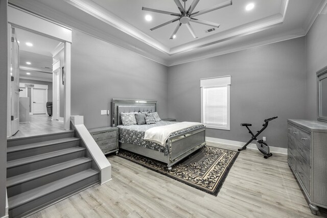 bedroom featuring a raised ceiling, ornamental molding, and light hardwood / wood-style floors