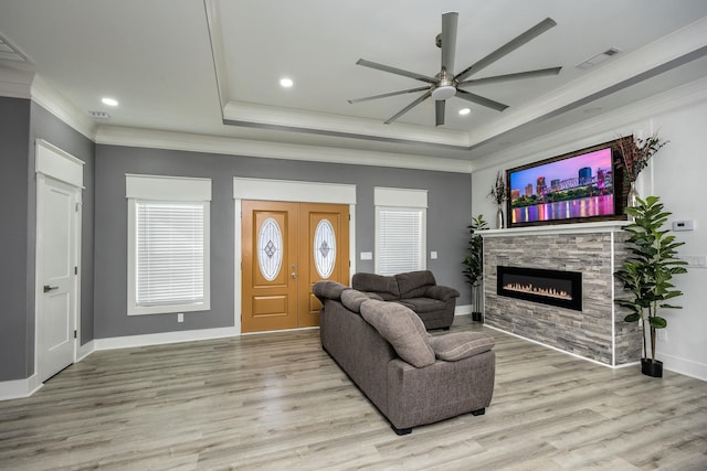 living room featuring ornamental molding, a raised ceiling, and light hardwood / wood-style flooring