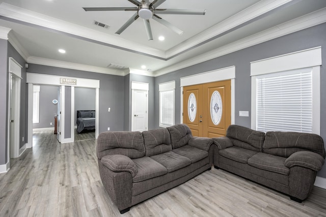 living room featuring crown molding, ceiling fan, a raised ceiling, and light wood-type flooring