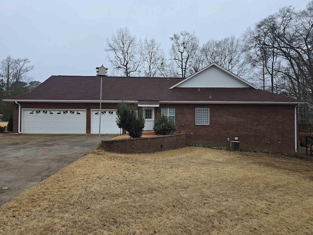 single story home featuring cooling unit, a garage, and a front yard