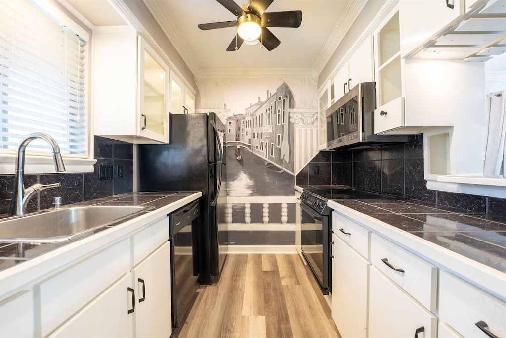 kitchen featuring sink, white cabinetry, crown molding, light wood-type flooring, and black appliances