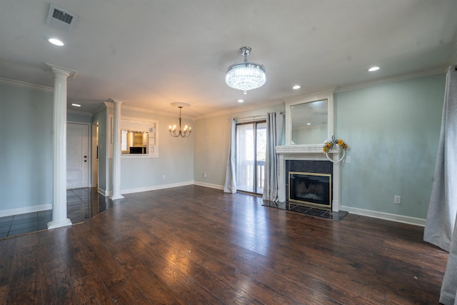 unfurnished living room with dark wood-type flooring, a fireplace, ornamental molding, a chandelier, and ornate columns