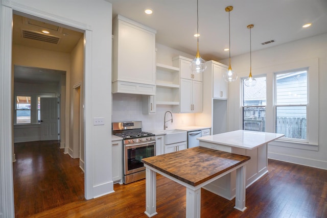 kitchen featuring pendant lighting, white cabinetry, stainless steel appliances, a kitchen island, and dark hardwood / wood-style flooring