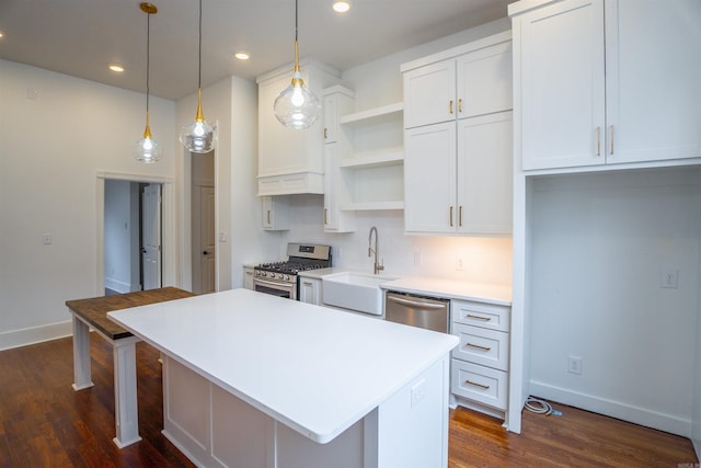 kitchen featuring pendant lighting, sink, stainless steel appliances, a center island, and white cabinets