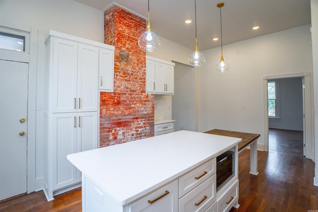 kitchen featuring a kitchen island, dark hardwood / wood-style floors, pendant lighting, built in microwave, and white cabinetry