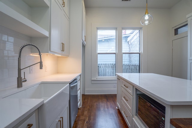 kitchen featuring pendant lighting, stainless steel dishwasher, black microwave, and white cabinets