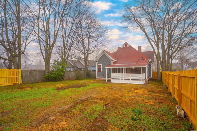 rear view of property featuring a yard and a sunroom