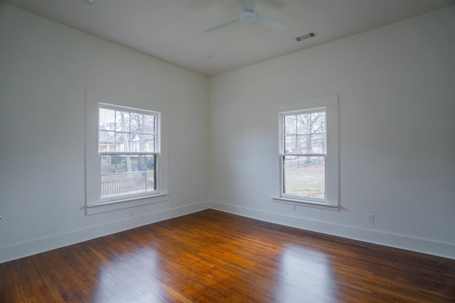 spare room featuring dark wood-type flooring, a wealth of natural light, and ceiling fan