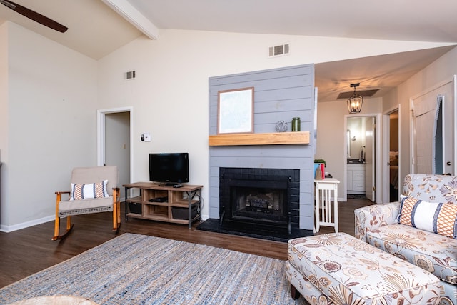 living room featuring vaulted ceiling with beams, dark wood-type flooring, and a large fireplace