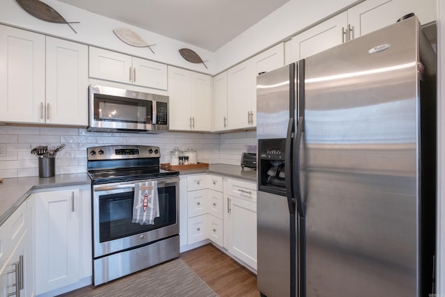 kitchen with stainless steel appliances, white cabinetry, and backsplash