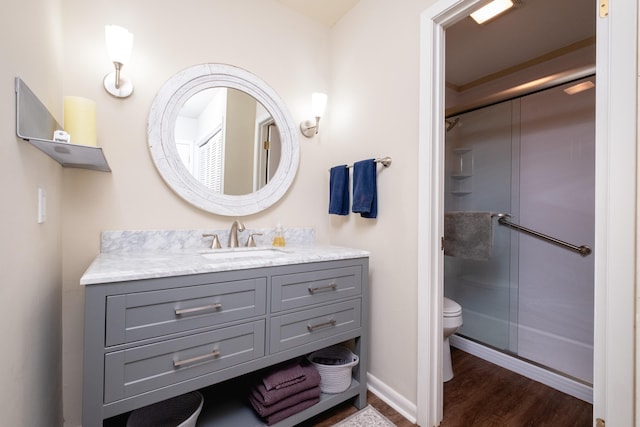 bathroom featuring vanity, hardwood / wood-style flooring, a shower with shower door, and toilet