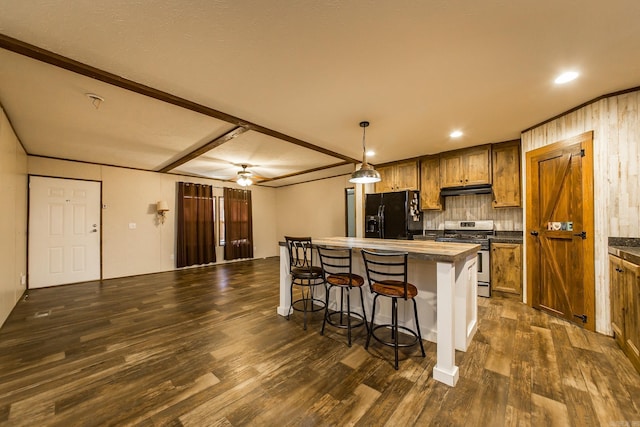 kitchen with a kitchen island, pendant lighting, a kitchen breakfast bar, gas stove, and black fridge