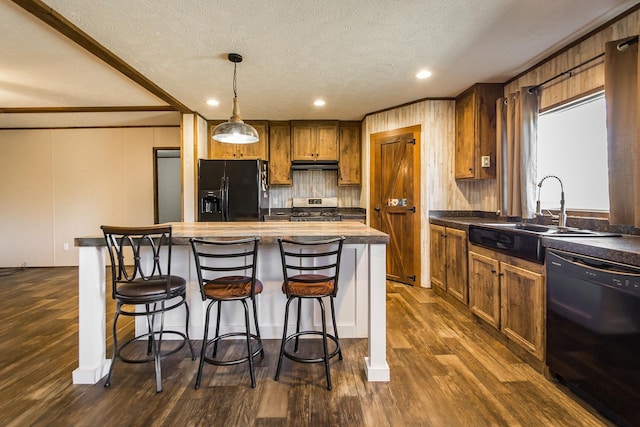 kitchen featuring sink, dark wood-type flooring, hanging light fixtures, backsplash, and black appliances