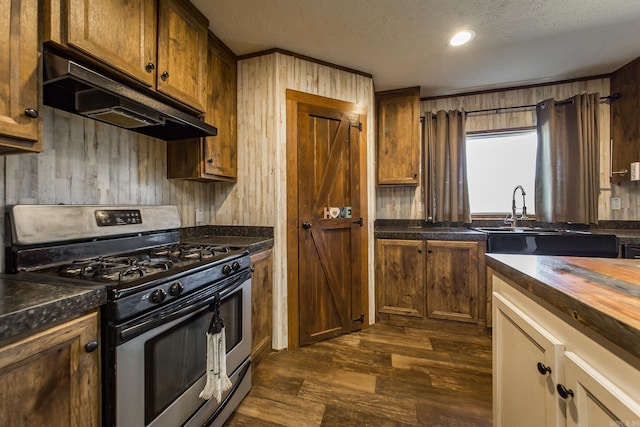 kitchen with sink, gas stove, wooden counters, a textured ceiling, and dark hardwood / wood-style flooring