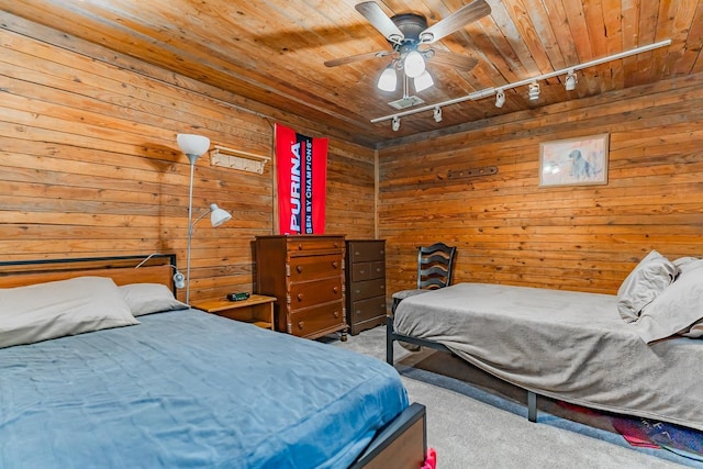 bedroom with wood walls, wooden ceiling, track lighting, carpet floors, and ceiling fan