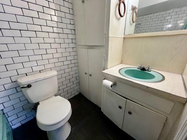 bathroom with tile walls, vanity, and toilet