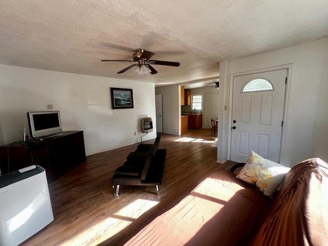 living room featuring dark hardwood / wood-style flooring, ceiling fan, and a textured ceiling