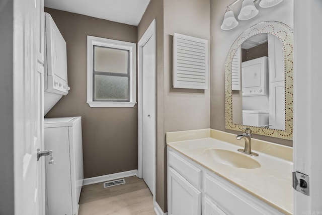 bathroom featuring vanity, hardwood / wood-style flooring, and stacked washer and clothes dryer