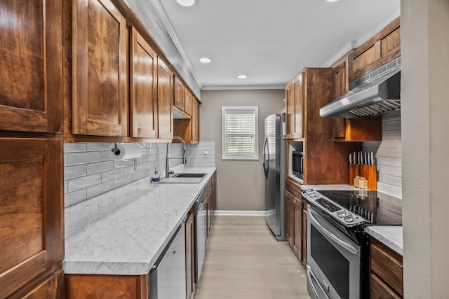 kitchen featuring sink, light hardwood / wood-style flooring, ornamental molding, stainless steel appliances, and decorative backsplash