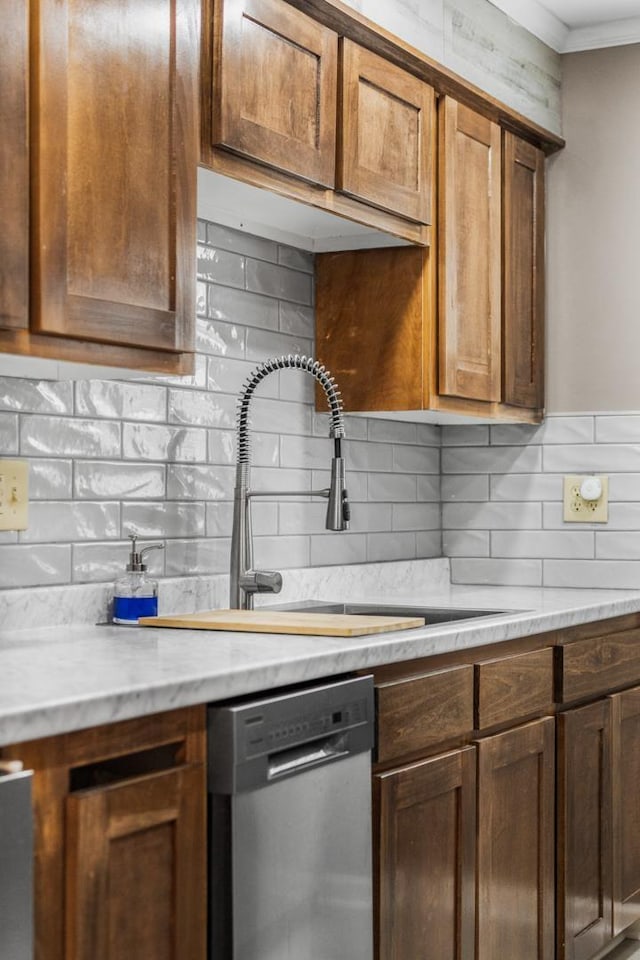 kitchen with sink, crown molding, light stone counters, stainless steel dishwasher, and backsplash