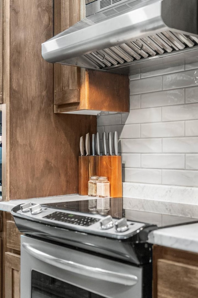 interior details with tasteful backsplash, exhaust hood, and electric range