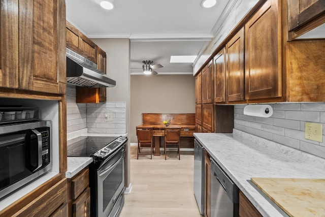 kitchen with appliances with stainless steel finishes, decorative backsplash, ornamental molding, ceiling fan, and light wood-type flooring