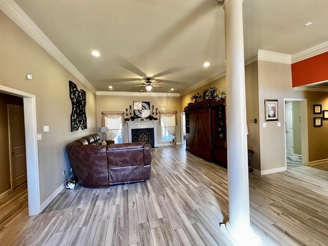 living room with crown molding, decorative columns, ceiling fan, and light wood-type flooring