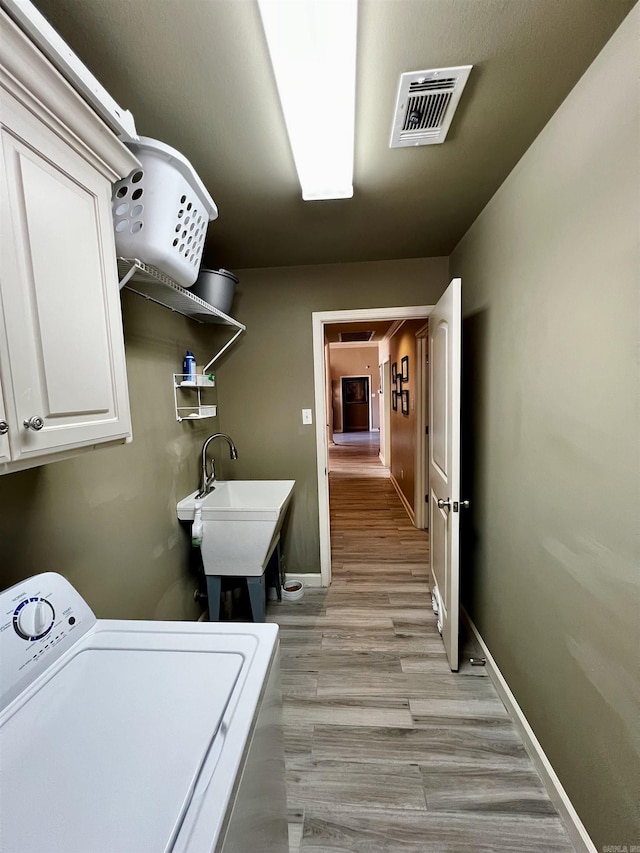 washroom with washer / clothes dryer, sink, cabinets, and light hardwood / wood-style flooring