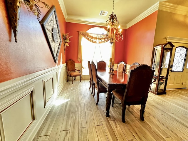 dining space with ornamental molding, a notable chandelier, and light hardwood / wood-style flooring