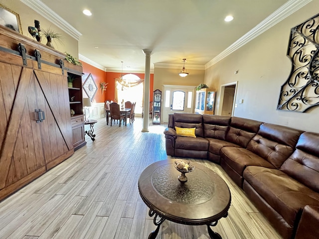 living room with light hardwood / wood-style flooring, ornamental molding, a barn door, and decorative columns