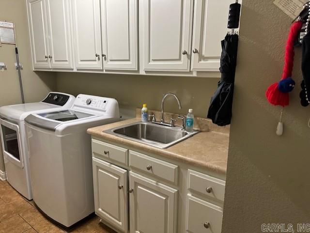 washroom featuring cabinet space, a sink, washing machine and clothes dryer, and light tile patterned floors