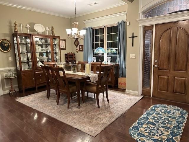 dining space with a notable chandelier, visible vents, ornamental molding, and wood finished floors