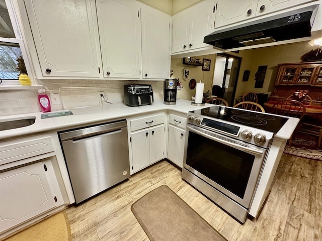 kitchen with stainless steel appliances, light hardwood / wood-style flooring, white cabinets, and kitchen peninsula