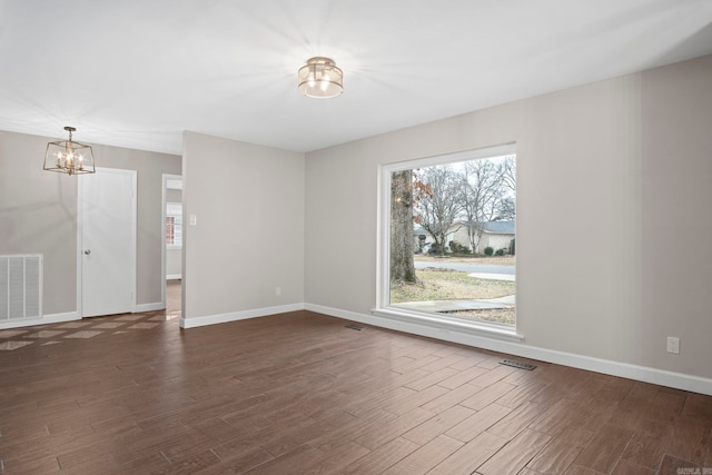 unfurnished room featuring a notable chandelier and dark hardwood / wood-style floors