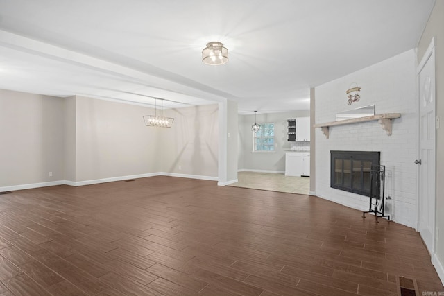 unfurnished living room with wood-type flooring, a chandelier, and a fireplace