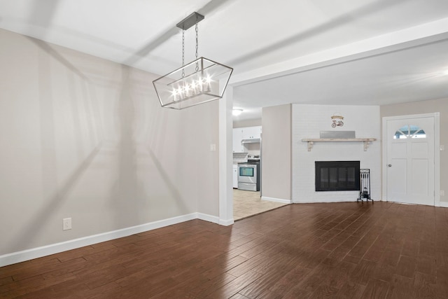 unfurnished living room with beamed ceiling, hardwood / wood-style floors, and a brick fireplace