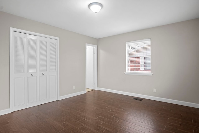 unfurnished bedroom featuring dark wood-type flooring and a closet