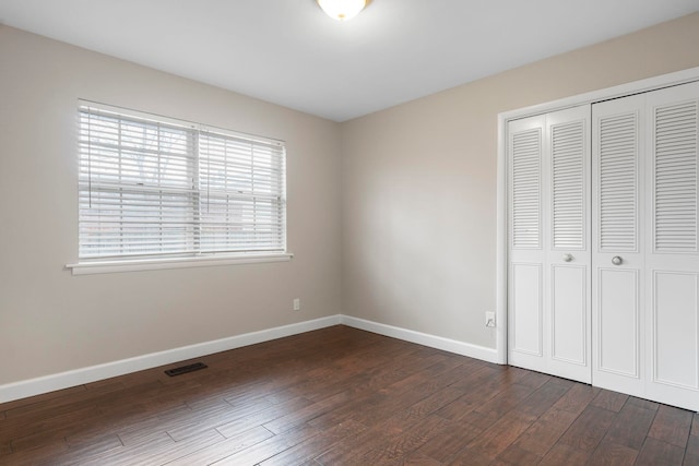 unfurnished bedroom with dark hardwood / wood-style flooring and a closet