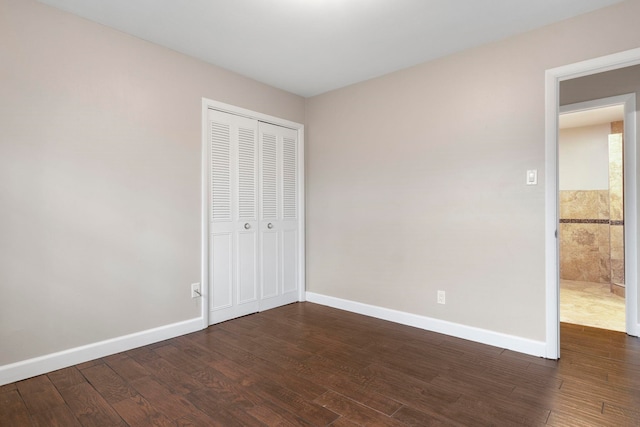 unfurnished bedroom with dark hardwood / wood-style flooring and a closet