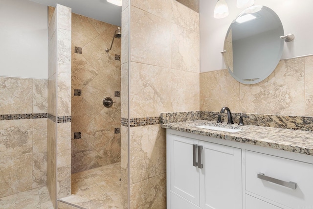 bathroom with tiled shower, vanity, and tile walls