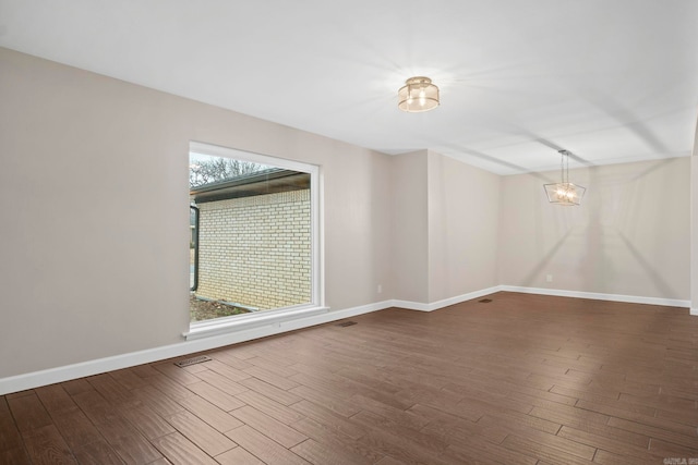 empty room featuring a chandelier and dark hardwood / wood-style flooring